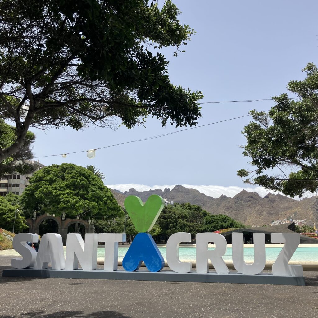 Large letters Santa Cruz near small lagoon with mountains in the background.