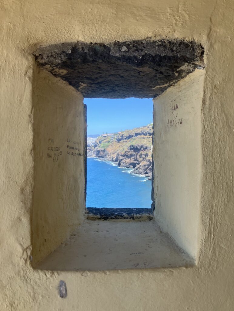 Small window in a fort looking out to ocean and cliff views