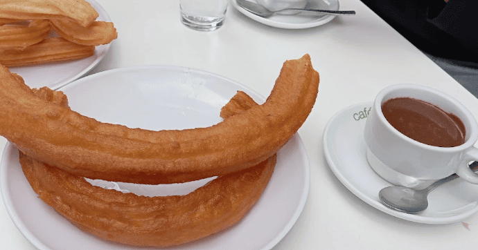 Fried dough with dipping chocolate on a white table at La Churrería Tradicional 