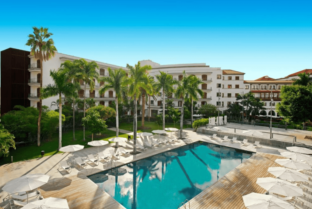 Hotels in Santa Cruz de Tenerife. Large outdoor pool surrounded by sun umbrellas.