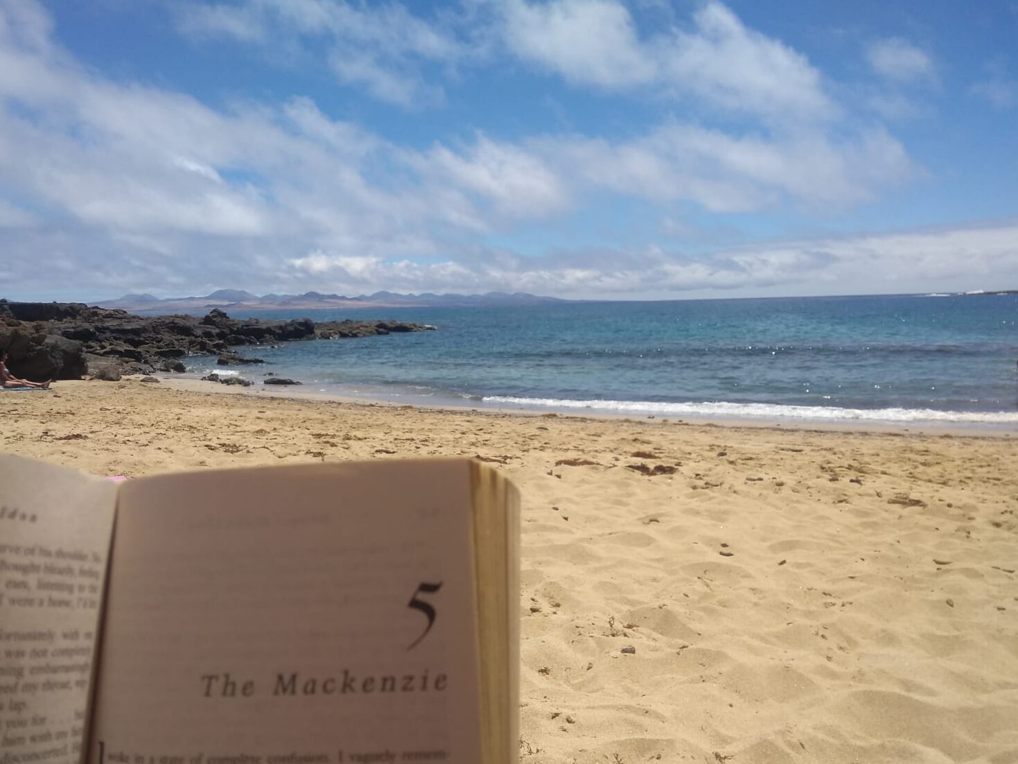 Virgin, white sand beach and ocean, someone reading a book in La Graciosa