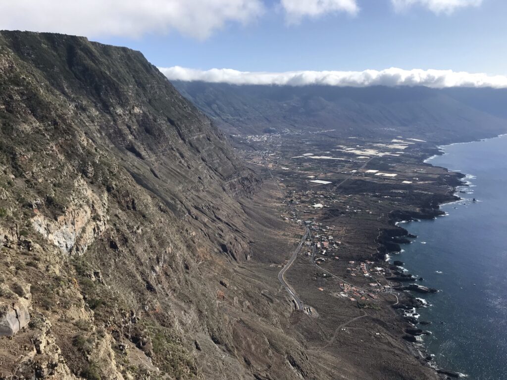 Expansive viewpoint overlooking a dramatic cliff, volcanic coastline and blue ocean in El Hierro island