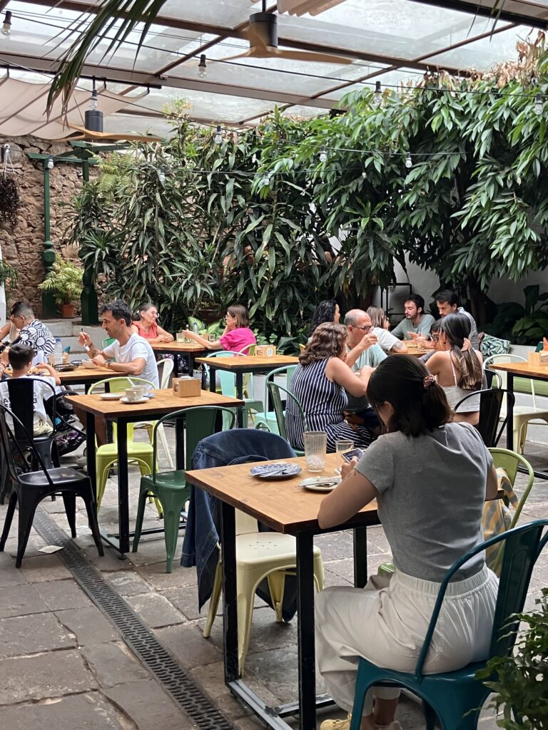 Coffee shop in interior patio. Many wooden tables and multicolored chairs. 
