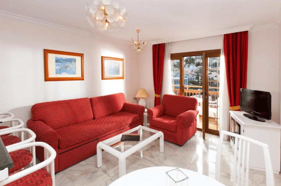 Apartamentos Casablanca living room space. Red sofa and chair and white interior design. 
