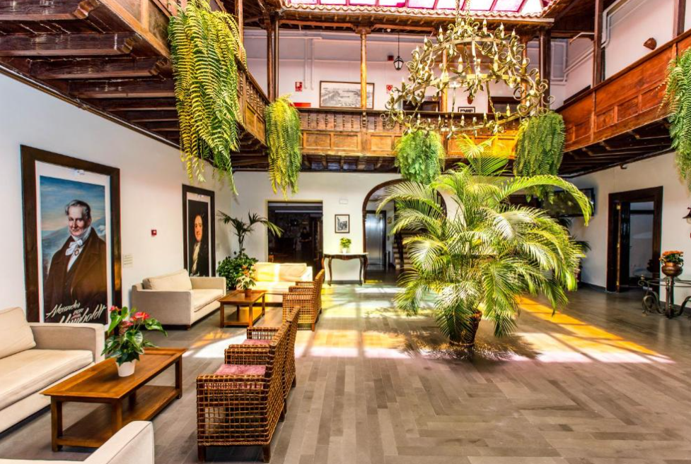 Interior courtyard at historic hotel Hotel Marquesa in Puerto de la Cruz. Wooden furniture, wooden balconies, chandelier and dangling ferms