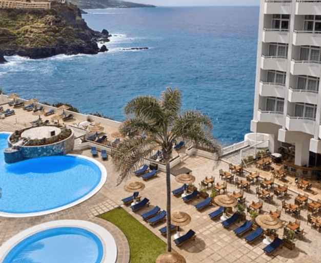 Precise Resort Tenerife: two round pools surrounded by pool loungers overlooking the ocean.