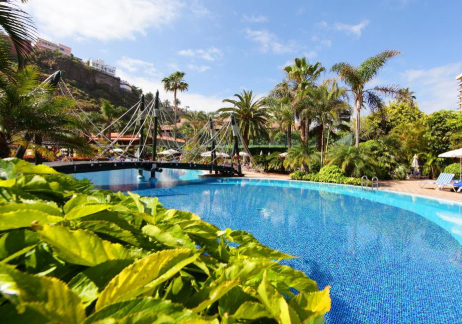 Large blue pool surrounded by green gardens and palm trees at Bahia Principe Explore San Felipe all-inclusive hotel in Puerto de la Cruz, Tenerife
