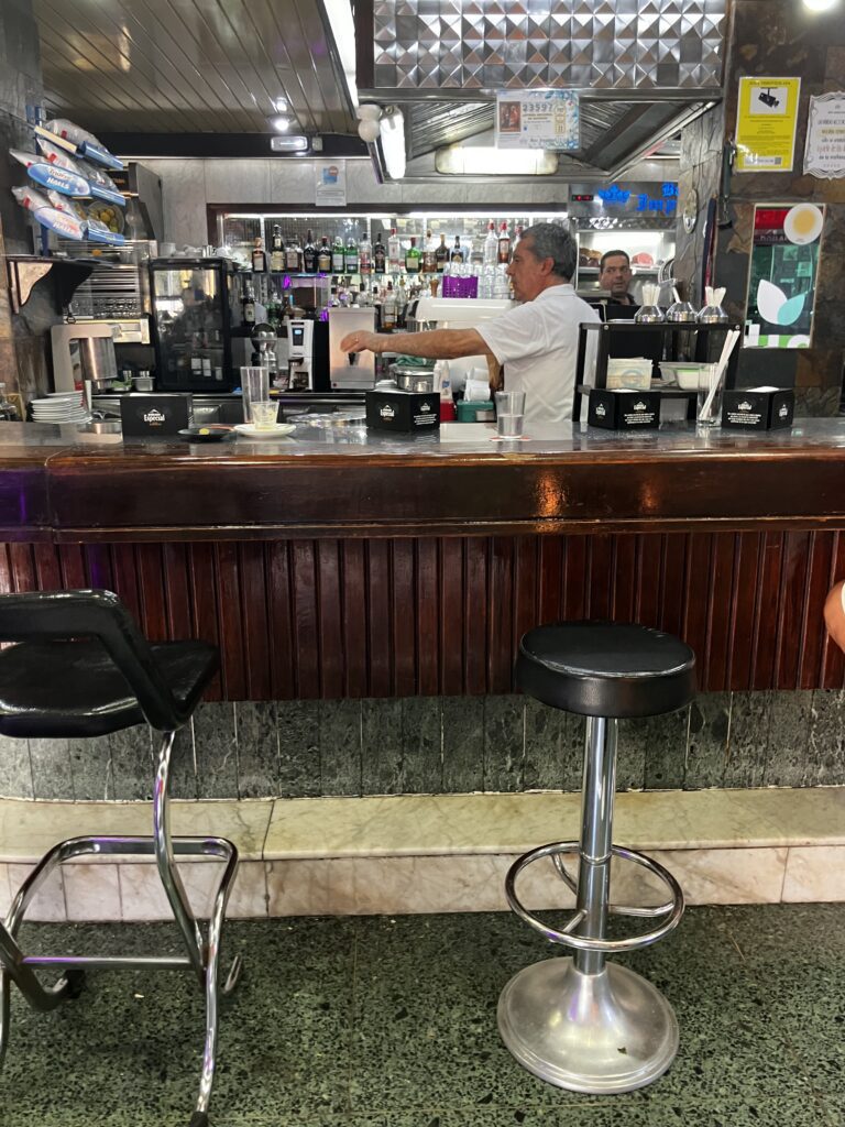 Two bar stool seats, a bar and one waiter at Bar Imperial. A typical spanish breakfast in santa cruz de tenerife
