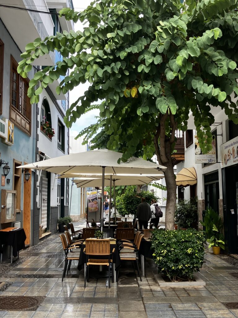 Pedestrian side street in Puerot de la Cruz, severla tables and chairs and sun umbrellas.