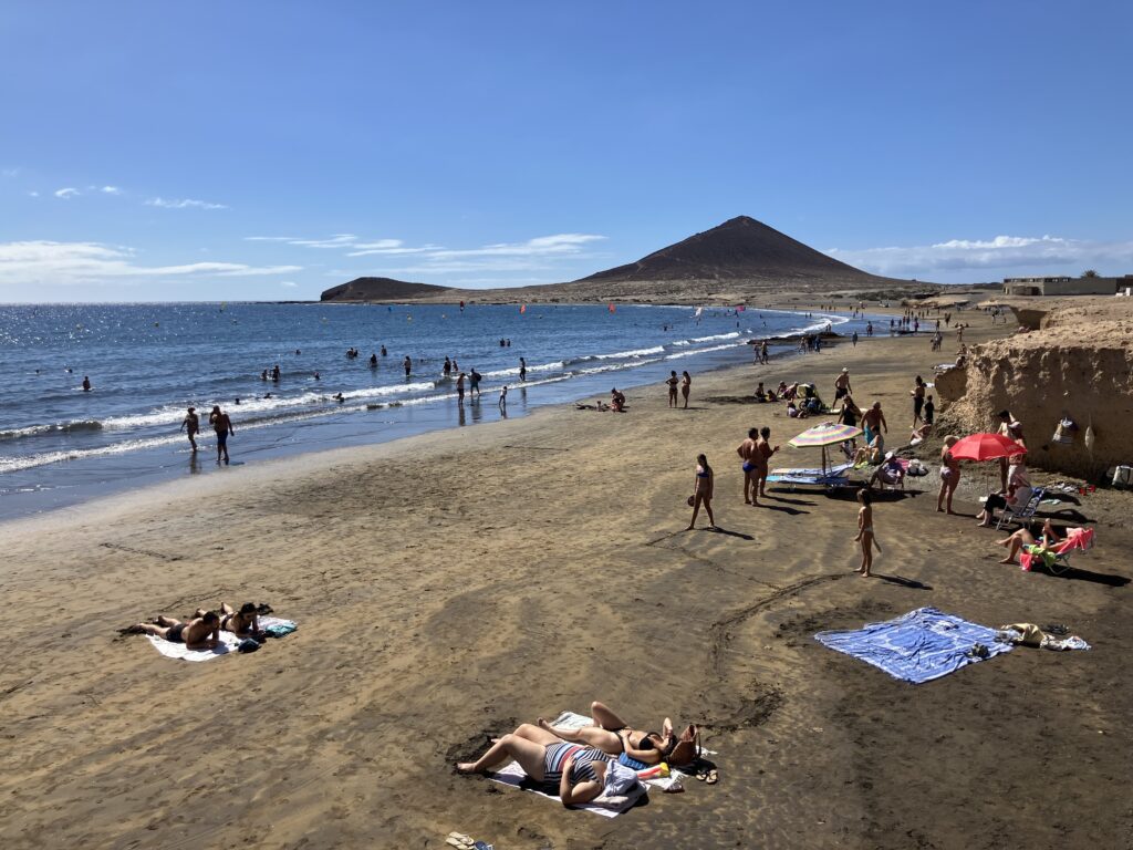 A beach in El Médano, Tenerife. People walking the beach, lying on the beach and swimming 