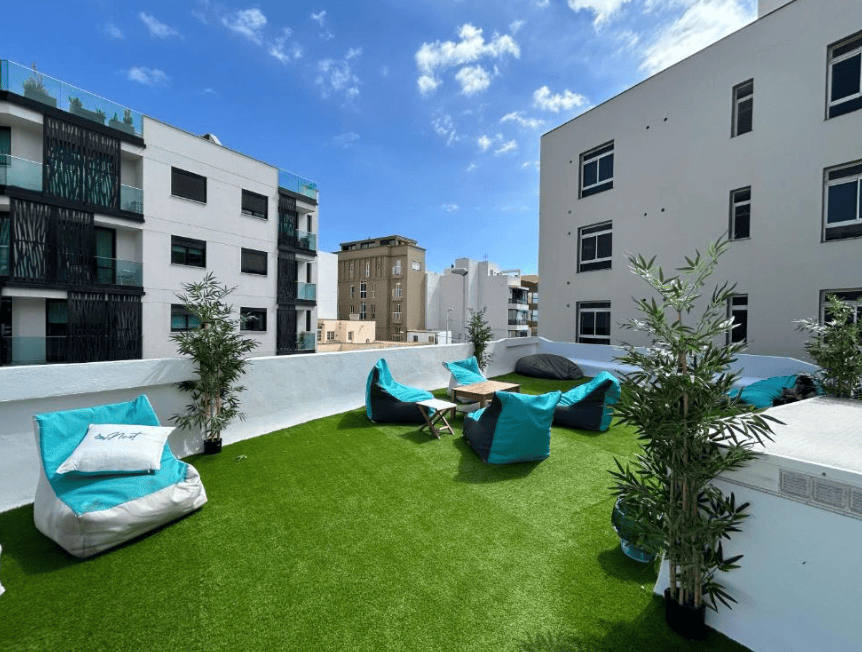Ashavana Nest Hostel rooftop. Fake green grass and lounge beanbag chairs
