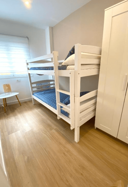 Bedroom photo with a bunk bed. White frame and blue sheets.