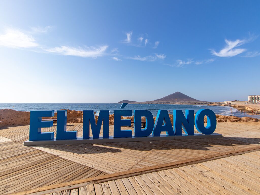 El Médano sign on a beach side boardwalk with ocean in the background
